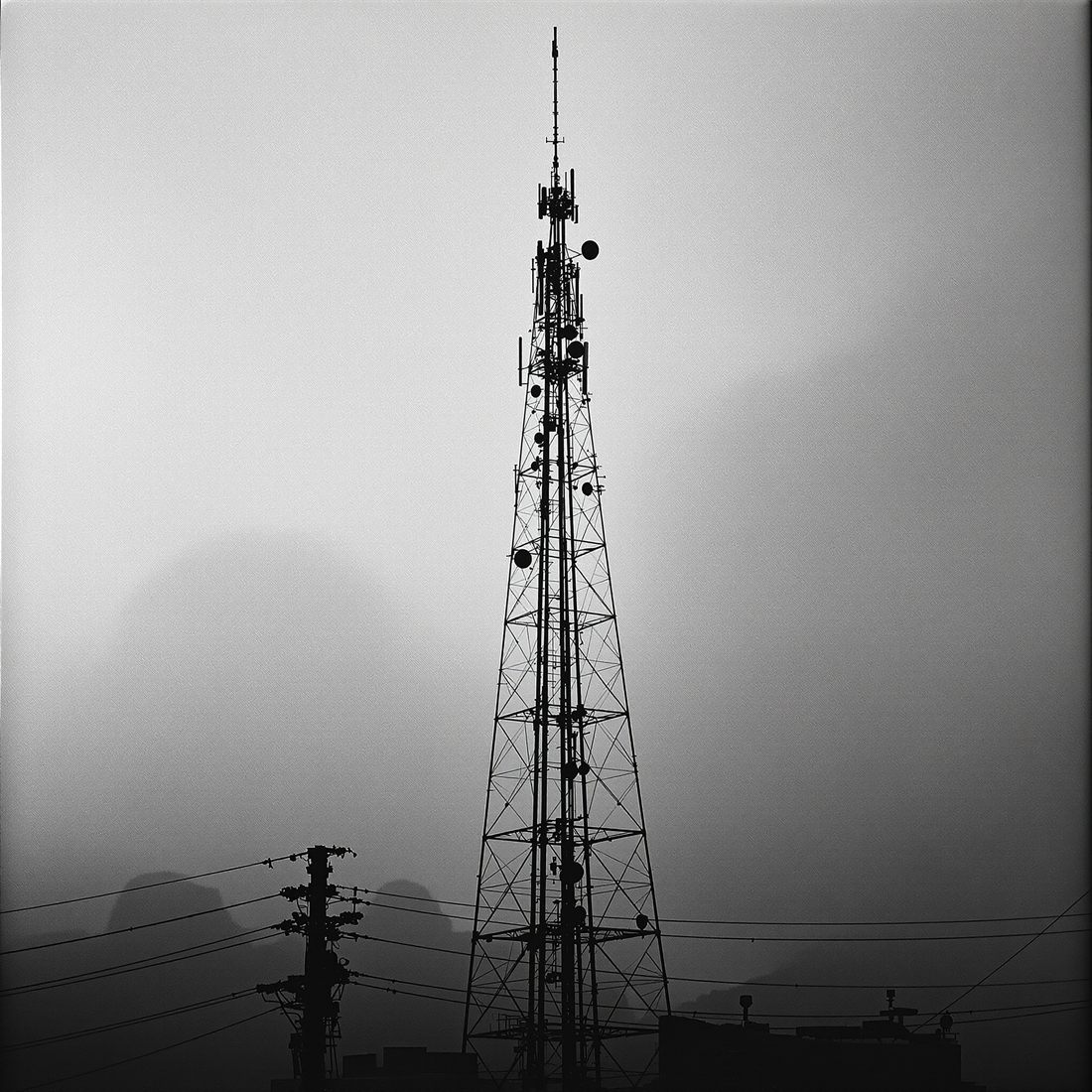 Antena de telecomunicaciones recortada contra la niebla